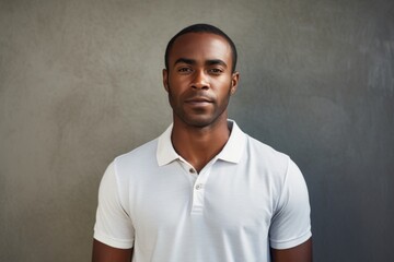 Obraz premium Portrait of a glad afro-american man in his 30s wearing a breathable golf polo isolated in bare concrete or plaster wall