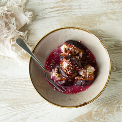 bowl of plums baked with ricotta and walnuts on the table
