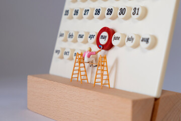 miniature people marking the month of may on the calendar