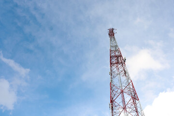 A tall tower with a red and white top is seen against a blue sky