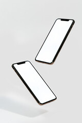 Two cell phones are in the air, one of which is white