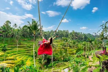 Fototapeten Bali Happy young female tourist in red dress enjoying the Bali swing at tegalalang rice terrace in Bali  © Kittiphan