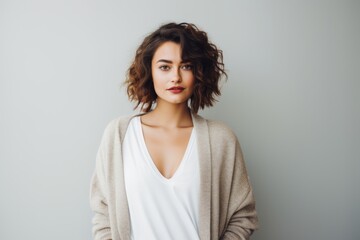 Obraz premium Portrait of a satisfied woman in her 20s wearing a chic cardigan on blank studio backdrop