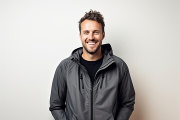 Obraz premium Portrait of a happy man in his 30s wearing a windproof softshell over light wood minimalistic setup