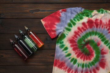 Vibrant Tie-Dye T-Shirt with Colorful Dye Bottles on Wooden Background