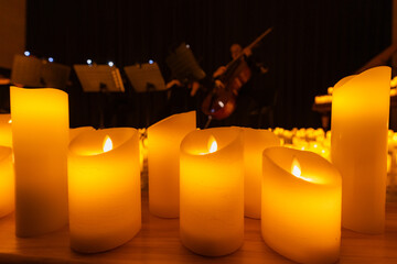 blurred symphonic orchestra on stage with lots of candles