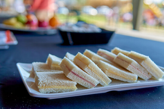 ham and cheese sandwiches de miga for lunch, typical argentinian snack on a table with blue tablecloth at a daytime event in a courtyard.