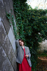 30-year-old medium-sized woman in a red muslin dress in an autumn garden