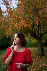 30-year-old medium-sized woman in a red muslin dress in an autumn garden