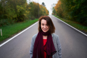 30-year-old medium-sized woman in a red muslin dress in an autumn garden