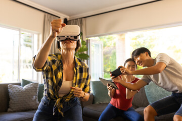 Using VR headset, mother playing game while family members watching and laughing