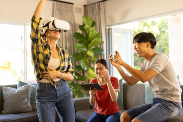 Playing VR game, mother wearing VR headset while family cheering and using tablet
