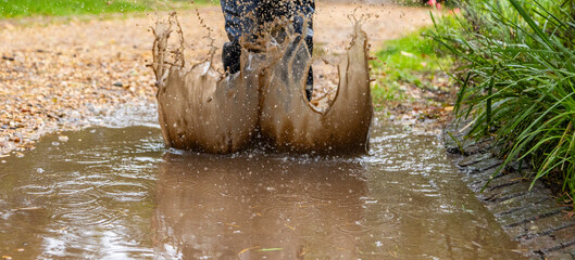 Child in welly boots, jump, jumping in mud.