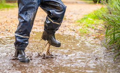 Child in welly boots, jump, jumping in mud.