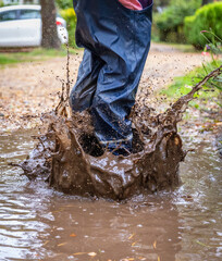 Child in welly boots, jump, jumping in mud.