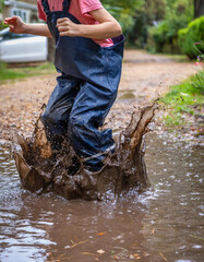 Child in welly boots, jump, jumping in mud.