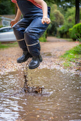 Child in welly boots, jump, jumping in mud.