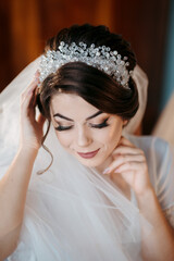 A woman with a white veil and a tiara on her head. She is smiling and looking at the camera