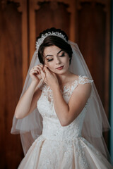 A woman in a wedding dress is looking at herself in the mirror. She is wearing a tiara and a veil