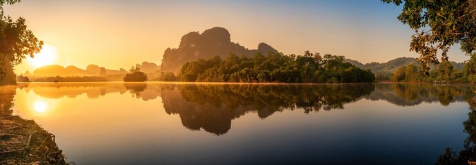 Panorama landscape peaceful sunrise over a lake with a boat in the distance at Nong Thale, Krabi, Thailand.