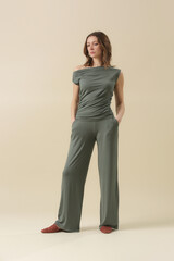 Fototapeta premium Female model wearing loungewear cotton soft and comfortable outfit, green top and trousers. Classic and simple fashion. Studio shot. 