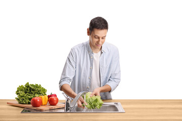 Young man washing vegetables in a sink