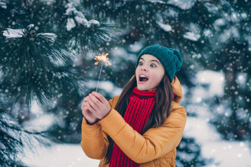 Portrait of attractive cheerful pre-teen girl wearing warm outfit burning bengal fire spark having...