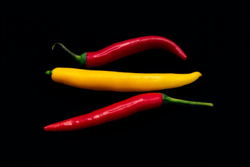 yellow and red hot chili peppers, black background