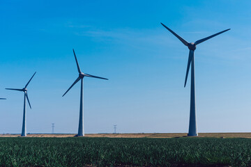 Metal modern windmills spinning with clean wind power generate electricity on innovative farm providing alternative energy