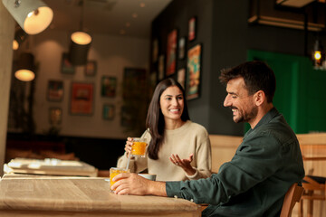 Couple enjoying at a cozy cafe with warm drinks and laughter in a vibrant, modern setting on a...