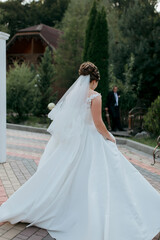 Obraz premium A woman in a white wedding dress is walking down a brick walkway. A man is standing behind her