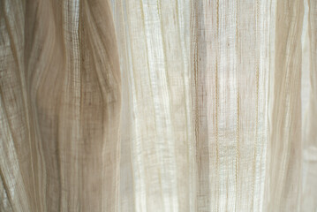 Light linen transparent fabric in beige against the background of light rays.