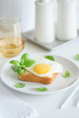 Croque madam sandwich with cheese and egg on white wooden table.