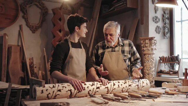 Young male listening to older experienced carpenter. Caucasian man explaining to apprentice or student how to continue working. Hugging boy while complementing on job. Showing well done.