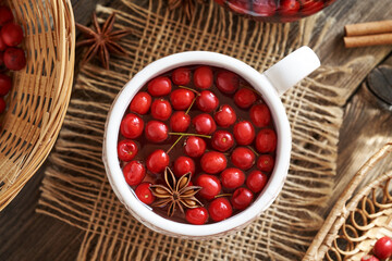 A cup of herbal tea with fresh wild hawthorn berries, top view