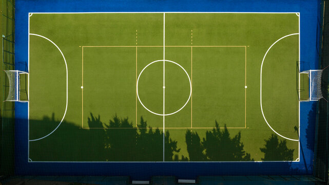 Perpendicular aerial view of an empty five-a-side football pitch. It has a synthetic grass pitch but there is no one in the sports centre.