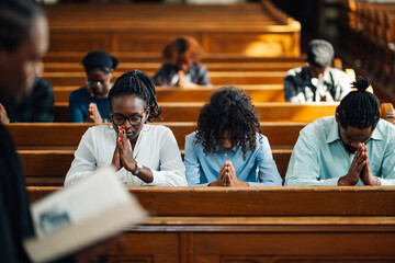 Congregation praying in church with priest holding bible