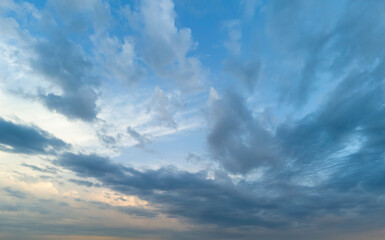A peaceful sky with soft, scattered clouds at sunset, showing natural shades of blue and orange. Perfect background for serenity, nature, or weather-themed projects.