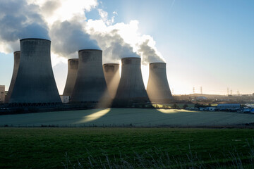 The sun shining behind power station cooling towers