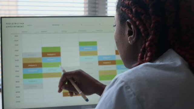 Over the shoulder view of female doctor looking at her work schedule on computer screen
