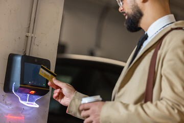 Businessman paying for parking ticket at car parking payment machine using credit card.