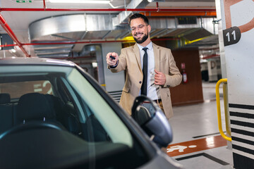 Young businessman unlocking his car with keys in an underground garage.