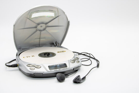 Close-up of a discman with the lid open with a CD and headphones isolated on white background