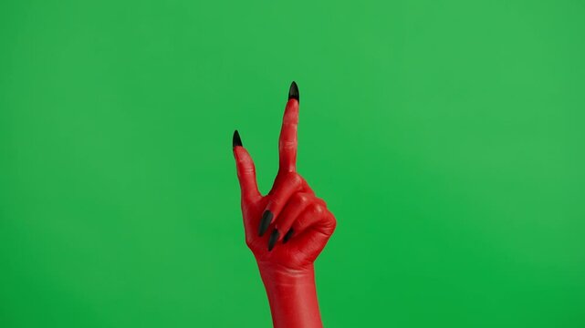 Creepy halloween devil monster hand in red paint with black nails pointing finger up, isolated on chroma key green screen background, workspace mockup.