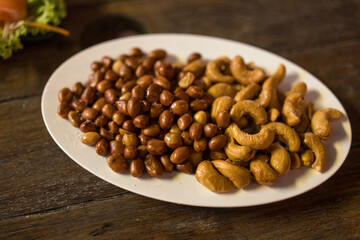 Peanut and cashew nut sprinkle salt in a dish on the wooden table