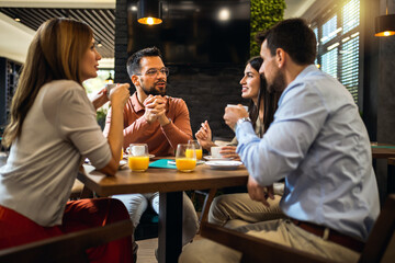 Group of friends hanging out at cafe, drinking coffee and orange juice.