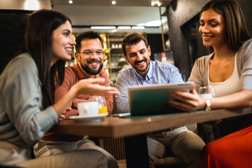 Group of friend met at the cafe. Looking at pictures on the phone. Having fun time together.