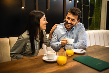 Lovely couple went on a date in a restaurant. Looking at each other and drink coffee.