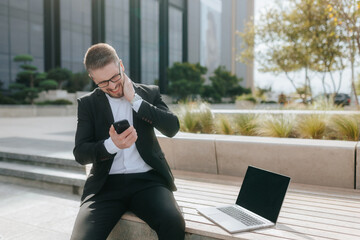 White-collar worker with a laptop and phone receives bad news, showing frustration