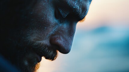 A moody and textured close-up profile of a male subject with a beard, captured in soft focus, highlighting the introspective and dramatic quality of the image.